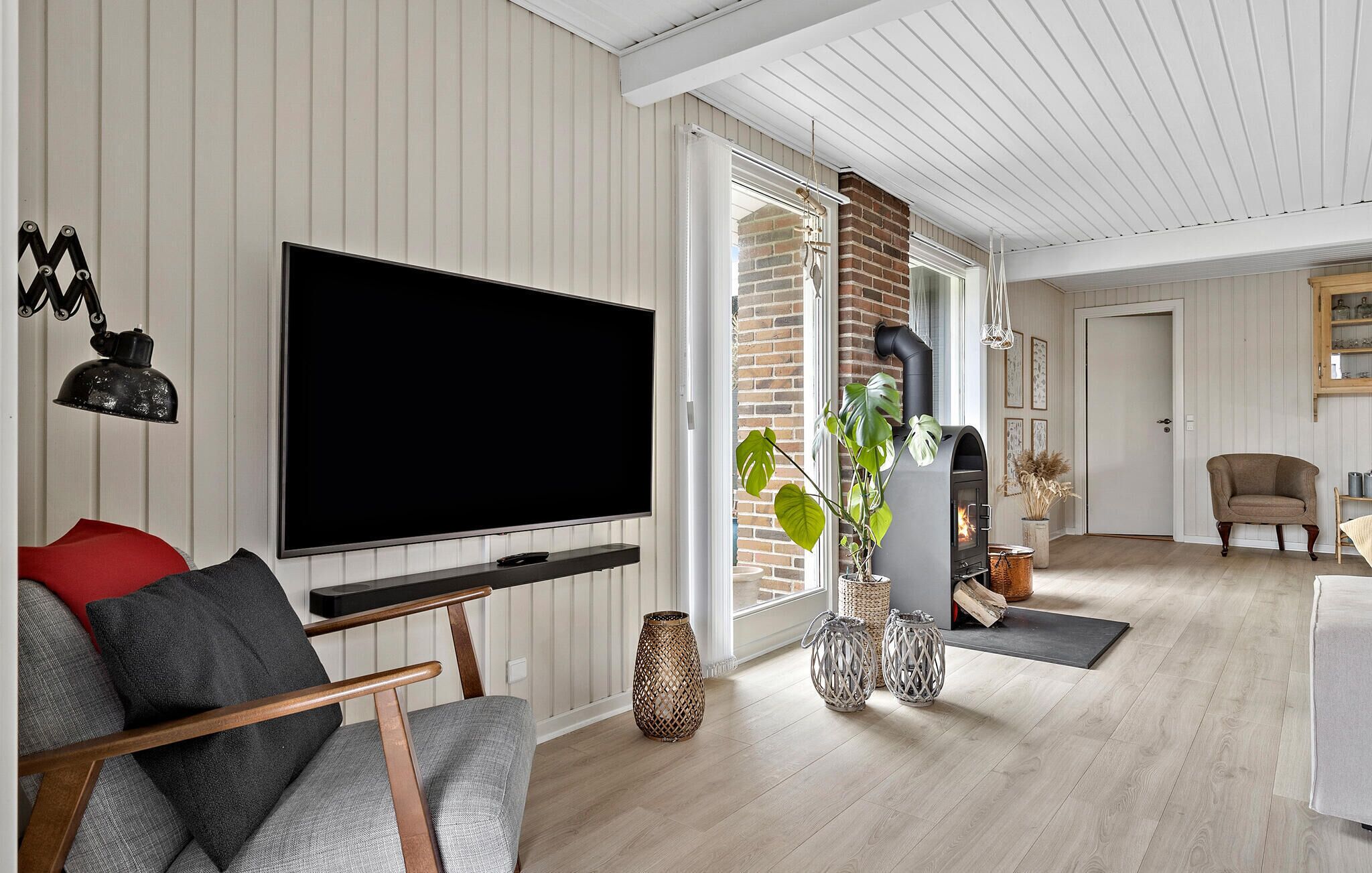 Moderni olohuone, jossa on suuri litteänäyttöinen televisio, takka ja mukava oleskelualue.