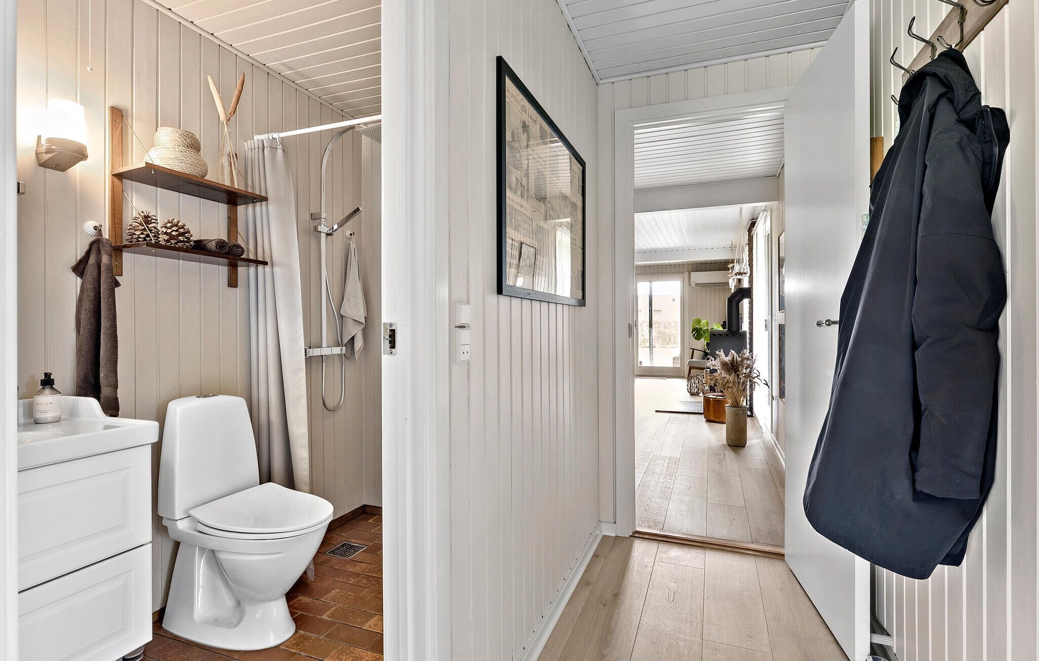 A bathroom with a toilet, a shower, and a towel rack.