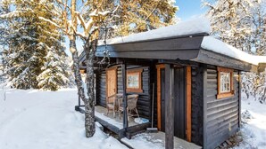 A log cabin with a porch and two windows, surrounded by snow-covered trees. - Stunning home in Gol with sauna (Gol)