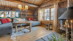A log cabin interior with a sofa, table, fireplace, and windows with a snowy view. - Stunning home in Gol with sauna (Gol)