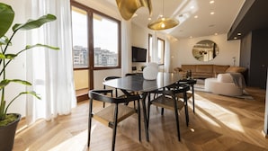 A modern living room with a dining area, large windows, and a view of the city. - Oro1 Florence Luxury Apartment by Mmega (Firenze)