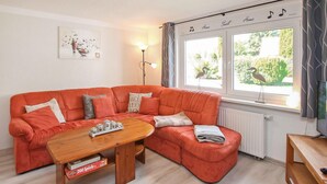 A cozy living room with a red sofa, a wooden coffee table, and a view of greenery outside. - Doppelhaushälfte Mirow Starsow (Mirow OT Starsow)