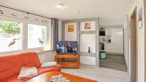 A living room with a sofa, a coffee table, a TV on a stand, and a kitchen in the background. - Doppelhaushälfte Mirow Starsow (Mirow OT Starsow)