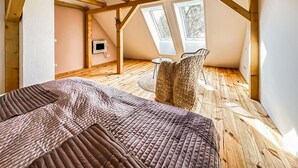 A loft bedroom with a wooden floor, a bed with a patterned bedspread, a woven chair, and two skylights. - 2 bedroom amazing home in Altwarp (Altwarp)