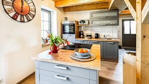 A modern kitchen with grey cabinets, a wooden countertop, a built-in oven, a microwave, and a coffee maker. - 2 bedroom amazing home in Altwarp (Altwarp)