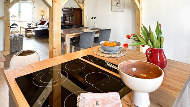 A kitchen with a wooden table, a bowl of fruit, a red vase with tulips, and a white bowl of soup. - 2 bedroom amazing home in Altwarp (Altwarp)