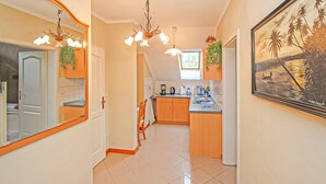 A hallway leading to a kitchen with wooden cabinets, a dining area, and a painting on the wall. - Ferienwohnung Wesenberg (Wesenberg OT Strasen)