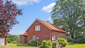 A red brick house with a gabled roof, a front garden, and a clear blue sky. - Ferienwohnung Wesenberg (Wesenberg OT Strasen)