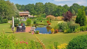 A lush garden with a pond, a gazebo, and a building in the background. - Ferienwohnung Wesenberg (Wesenberg OT Strasen)