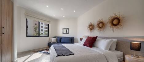 A modern bedroom with a large bed, a wooden wardrobe, a window with a view, and decorative wall art.