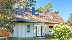 Ein eingeschossiges Haus mit Ziegeldach, Schornstein und einer Haustür mit kleiner Veranda.