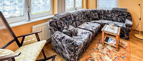 Een moderne woonkamer met een gebogen modulaire bank, een houten salontafel en een kamerkleed met een patroon.