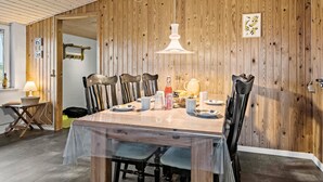 A dining area with a wooden table, chairs, and a hanging light fixture.