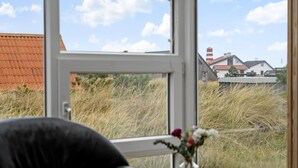 A view from a window with a view of a house, grass, and a red-roofed building.