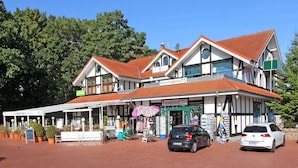 A two-story building with a traditional architectural style, featuring a red-tiled roof and white walls.