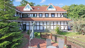 A two-story house with a red-tiled roof, white walls with black trim, and a balcony.