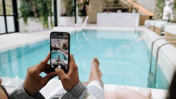 Una persona relaxant-se al costat d'una piscina, aguantant un telèfon mòbil.