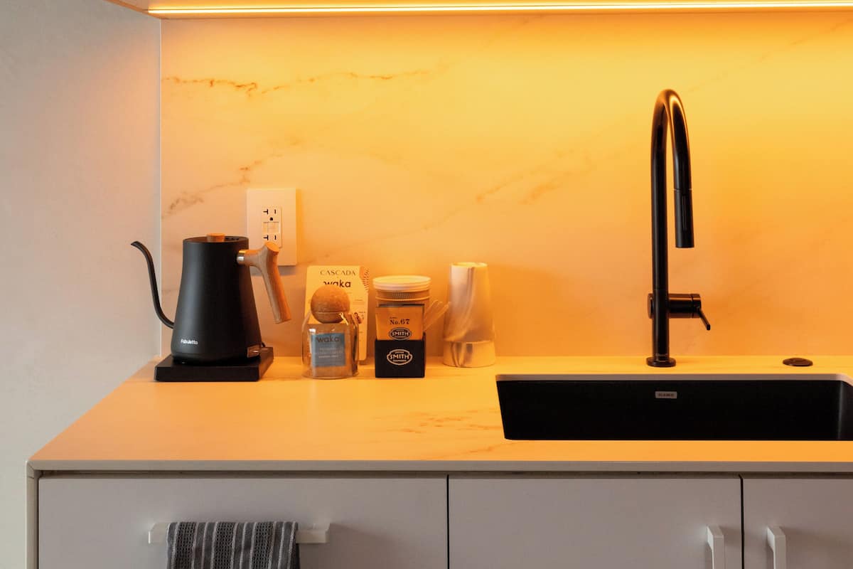 A modern kitchen with a black faucet, a coffee maker, and a sink.