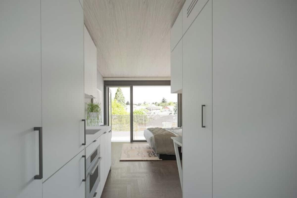 A modern, minimalist bedroom with a large window, a bed, and a view of the outdoors.