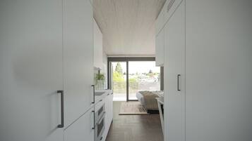 A modern, minimalist bedroom with a large window, a bed, and a view of the outdoors.