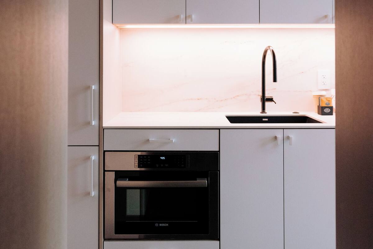 A modern kitchen with white cabinets, a Bosch oven, and a sink.