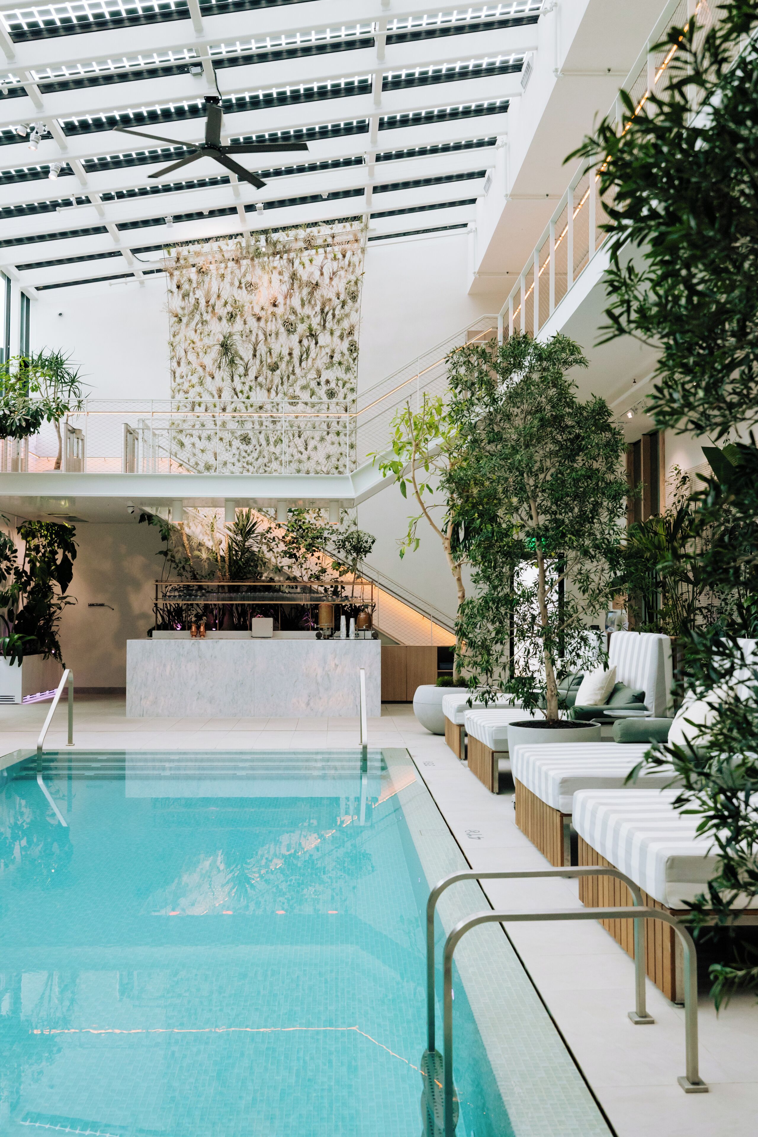 Una piscina interior con ventilador de techo, mostrador de recepción y asientos de sala de estar.