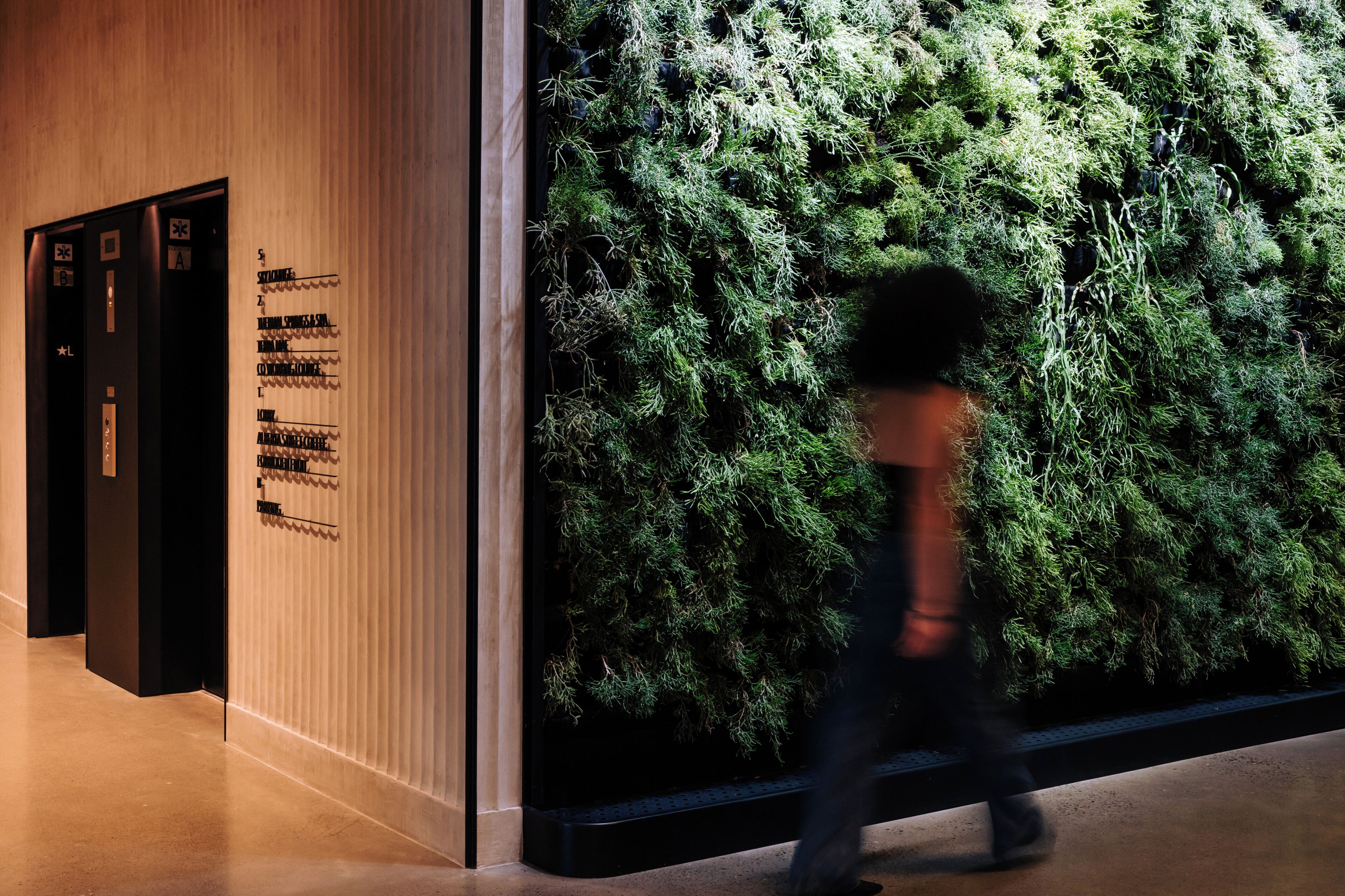 A modern lobby with a vertical garden wall, a reception desk, and a staircase.