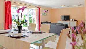 A dining area with a table set for two, a potted orchid, and a view of the outdoors through large windows. - 3 bedroom gorgeous home in Verchen (Verchen)