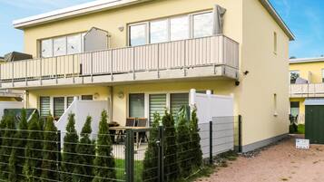 Ein zweistöckiges Gebäude mit Balkon, umzäunter Garten und einem Schild, das freie Parkplätze anzeigt.