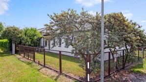 A fenced property with a white building, a tree, and a clear sky. - 2 bedroom cozy home in Gahlkow (Gahlkow)