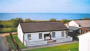 A white building with a tiled roof, a front porch, and a view of the sea. - 2 bedroom cozy home in Gahlkow (Gahlkow)