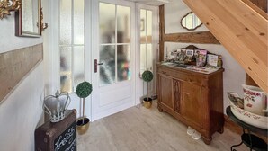 A hallway with a wooden staircase, a wooden cabinet with various items, and a door with frosted glass panels. - Ferienwohnung Rheinsberg (Rheinsberg)
