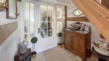 Ein Flur mit einer Holztreppe, einem Holzschrank mit diversen Gegenständen und einer Tür mit Milchglasfenstern.
