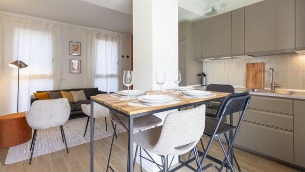 Cozinha moderna com mesa de madeira posta para refeições, um sofá e uma cadeira de jantar.