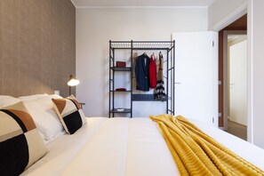 Hotellihuone, jossa on sänky, vaatekaappi, lamppu ja keltainen peitto.