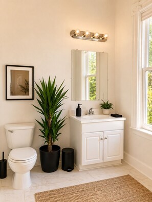 A bathroom with a toilet, sink, mirror, and potted plants. - Spacious Downtown Retreat by Beale Street & FedEx Forum+Parking (Memphis)