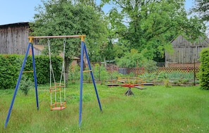 A playground with swings and a seesaw in a grassy area with trees and a wooden fence in the background. - 2 bedroom pet friendly apartment in Zirtow (Zirtow)