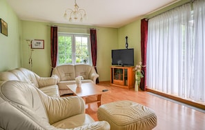 A living room with a sofa set, a coffee table, a TV on a stand, and a window with curtains. - 2 bedroom pet friendly apartment in Zirtow (Zirtow)