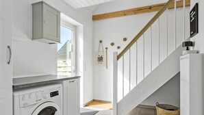 Ein Waschraum mit Waschmaschine, Wäscheständer und einer Holztreppe.