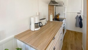 Una cocina compacta con encimera de madera, cafetera, tostadora, hervidor y microondas.
