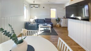 Una sala de estar moderna con un sofá gris, una mesa de centro blanca y un televisor montado en la pared.