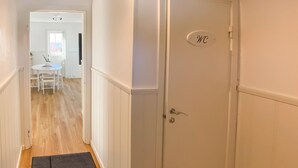 Un pasillo con piso de madera que conduce a una habitación con una puerta que indica 'WC'.