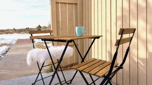 A wooden bench and table set against a wooden wall, with a blue cup on the table. - Taos retreat with steam shower and mountain views (El Prado)