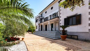 Un edificio con fachada blanca, un balcón y un patio empedrado.