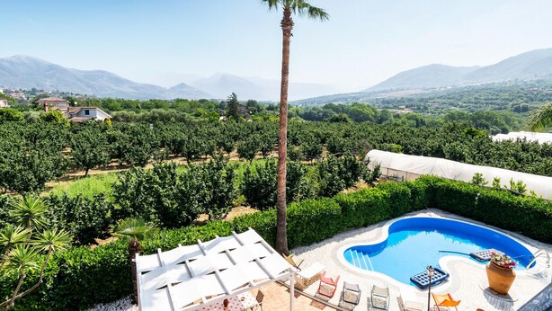 Zona de piscina con sillas de descanso y vistas a viñedos y montañas.