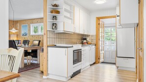 Une cuisine moderne avec des meubles blancs, un îlot central en bois et un four encastré.