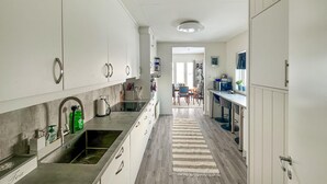 A modern kitchen with white cabinetry, a stainless steel sink, and a wooden floor.