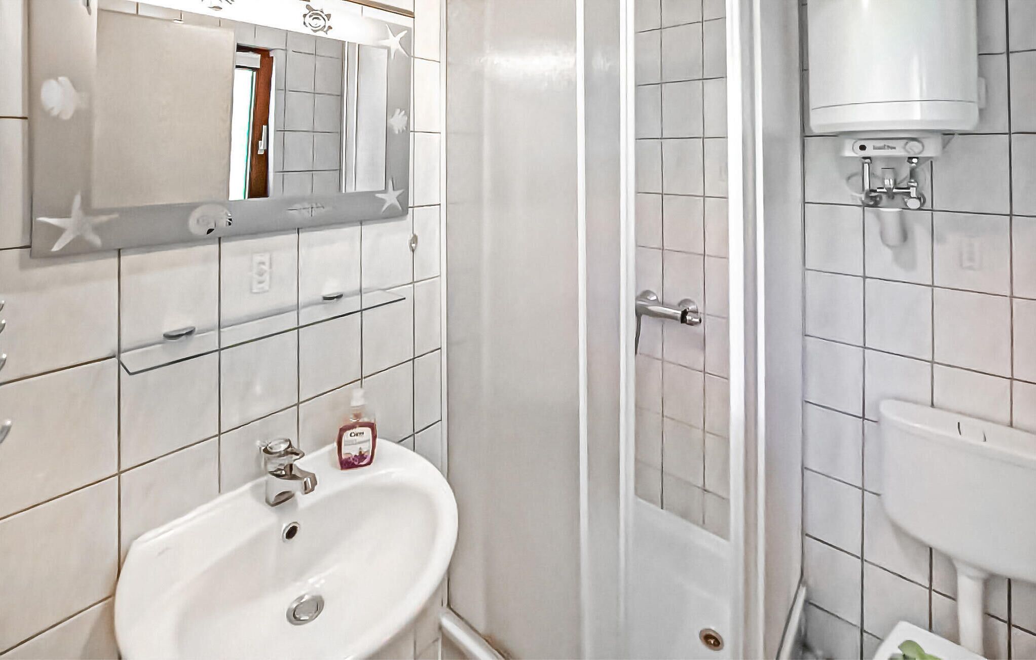 Ein Badezimmer mit einem weißen Waschbecken, einem Spiegel und einer Duschkabine.