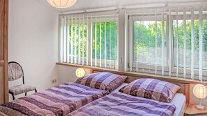 A bedroom with two beds, a chair, and a window with blinds. - Amazing apartment in Klink with sauna (Klink)