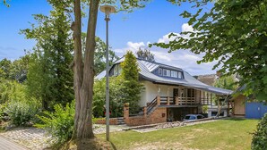 A two-story house with a sloped roof, a visible staircase, and a paved driveway. - Amazing apartment in Klink with sauna (Klink)